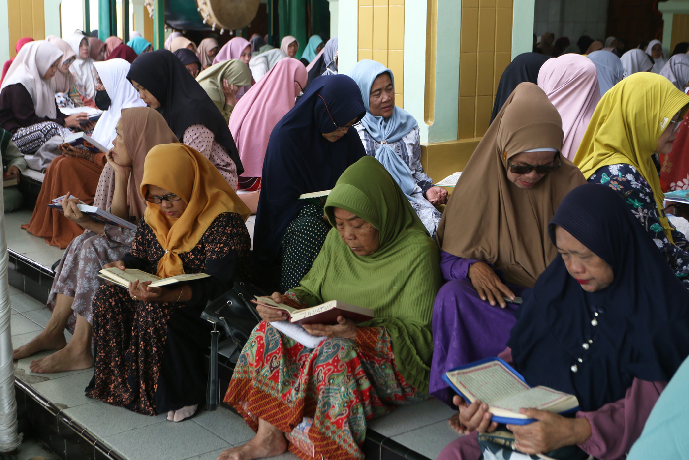 Sejumlah warga menyimak bacaan Al Quran yang disampaikan oleh seorang hafidz (penghafal) saat mengik