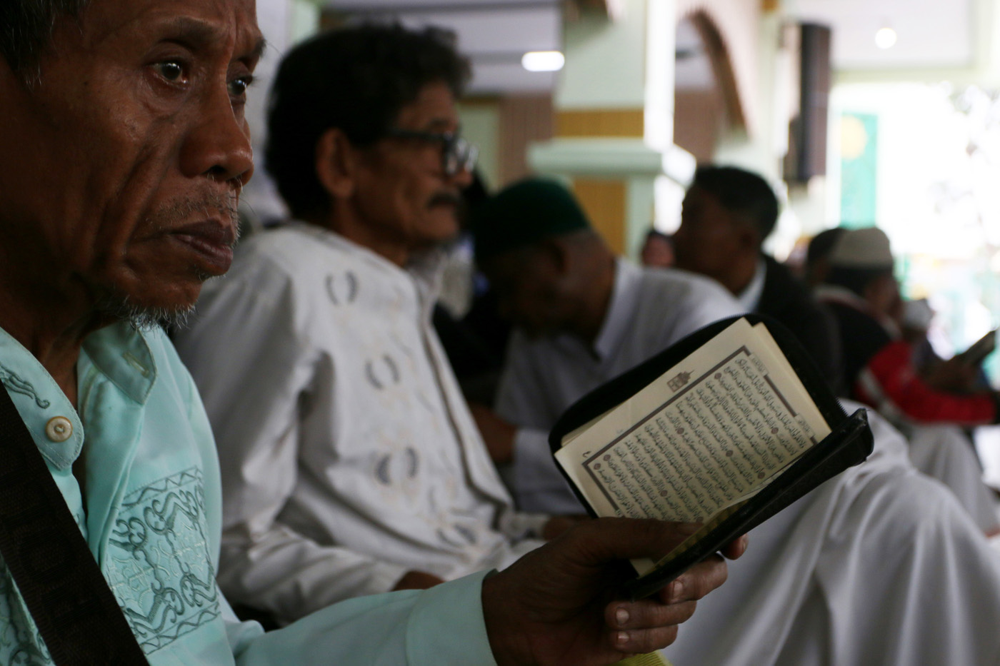 Sejumlah warga menyimak bacaan Al Quran yang disampaikan oleh seorang hafidz (penghafal) saat mengik