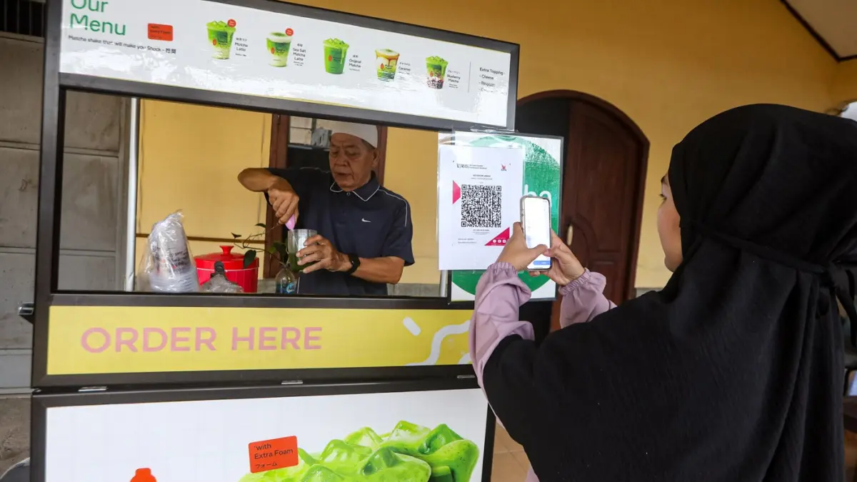 Warga membayar menggunakan kode batang QRIS di salah satu gerai UMKM di Depok, Jawa Barat, Rabu (25/2/2026). (Salman Toyibi/Jawa Pos)