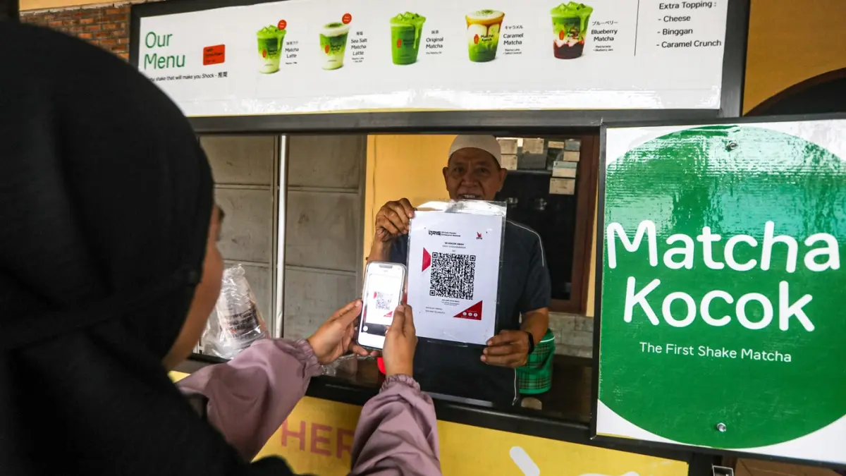 Warga membayar menggunakan kode batang QRIS di salah satu gerai UMKM di Depok, Jawa Barat, Rabu (25/2/2026). (Salman Toyibi/Jawa Pos)