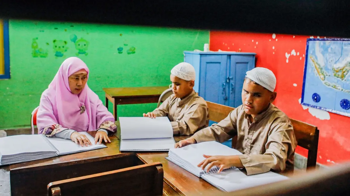 Guru Siswa SLB YPAB Tegalsari, Tantri Maharani membimbing siswa mengaji braille dalam rangka mengisi momen Ramadan di Kawasan Tegalsari. (Riana Setiawan/Jawa Pos)