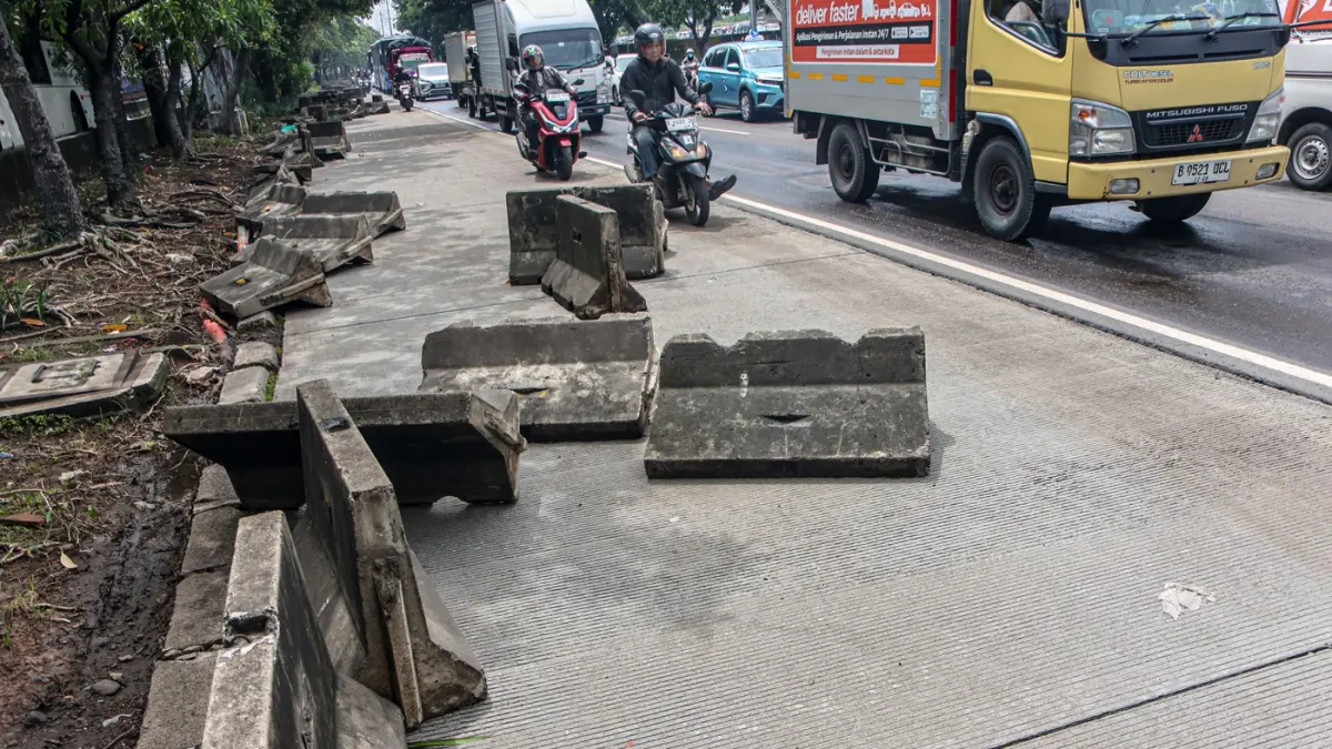 Pengendara melintas di samping pembatas jalur Transjakarta berantakan pasca banjir yang menggenangi jalan Daan Mogot, Jakarta, Senin (9/3/2026). (Hanung Hambara/Jawa Pos)