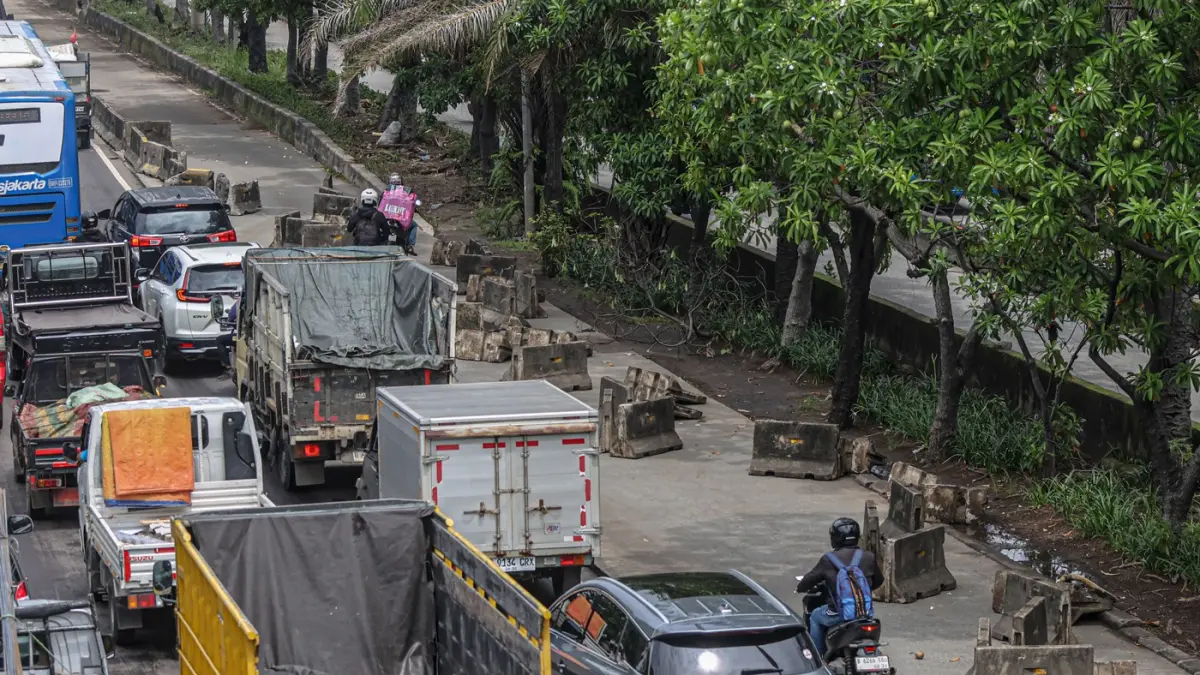 Pengendara melintas di samping pembatas jalur Transjakarta berantakan pasca banjir yang menggenangi jalan Daan Mogot, Jakarta, Senin (9/3/2026). (Hanung Hambara/Jawa Pos)