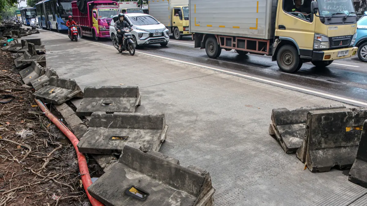 Pengendara melintas di samping pembatas jalur Transjakarta berantakan pasca banjir yang menggenangi jalan Daan Mogot, Jakarta, Senin (9/3/2026). (Hanung Hambara/Jawa Pos)