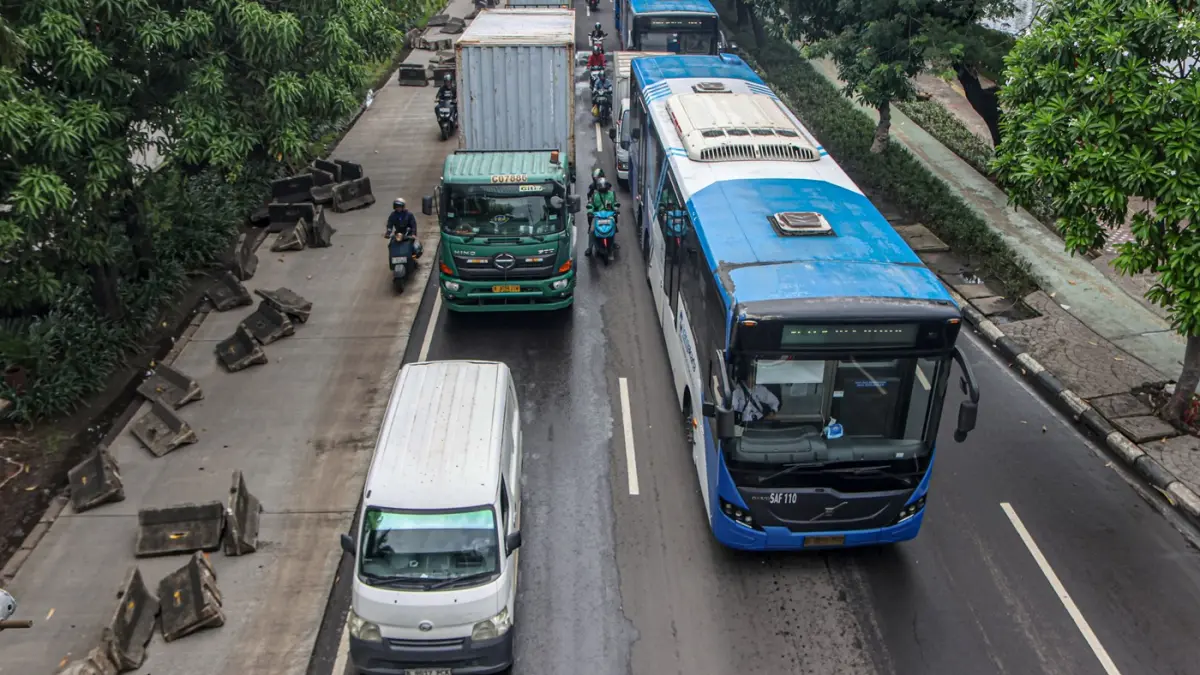 Pengendara melintas di samping pembatas jalur Transjakarta berantakan pasca banjir yang menggenangi jalan Daan Mogot, Jakarta, Senin (9/3/2026). (Hanung Hambara/Jawa Pos)
