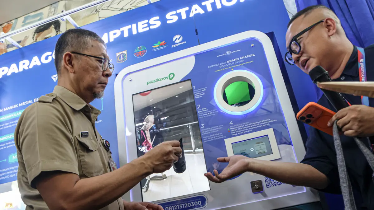 Wakil Kepala Dinas Lingkungan Hidup (DLH) DKI Jakarta Dudi Gardesi Asikin (kiri) memasukan sampah kosmetik ke mesin smart drop box sampah di Halte Transjakarta Cakra Selaras Wahana, Jakarta, Selasa (07) 04/2026). (Hanung Hambara/Jawa Pos)
