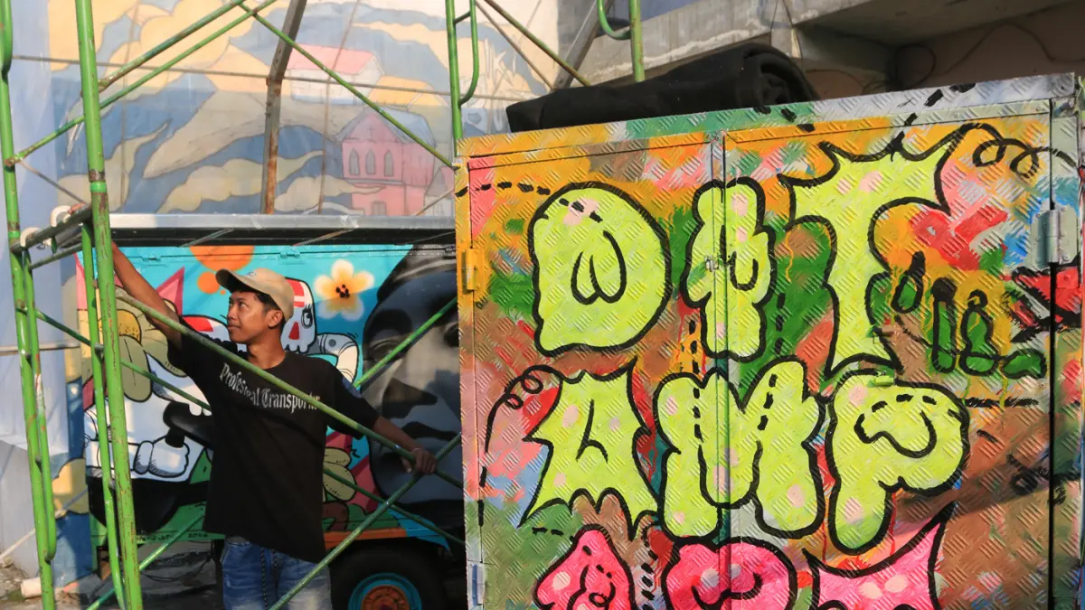 Seniman menyelesaikan mural bertema “Aturan Awuren” di tembok Kampung Petemesan, Pekojan, Semarang. (Nur Chamim/ Jawa Pos Radar Semarang)