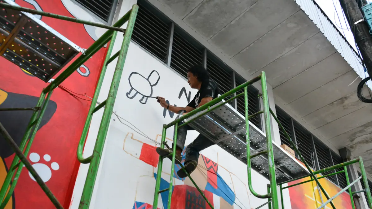 Seniman menyelesaikan mural bertema “Aturan Awuren” di tembok Kampung Petemesan, Pekojan, Semarang. (Nur Chamim/ Jawa Pos Radar Semarang)