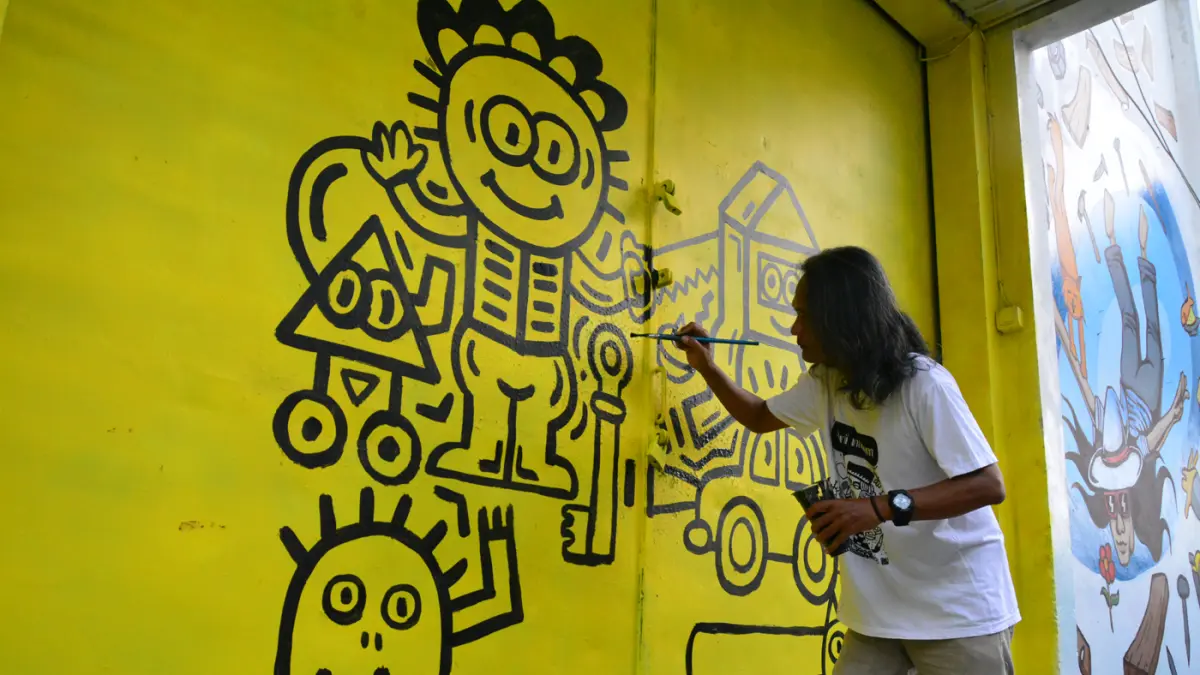 Seniman menyelesaikan mural bertema “Aturan Awuren” di tembok Kampung Petemesan, Pekojan, Semarang. (Nur Chamim/ Jawa Pos Radar Semarang)