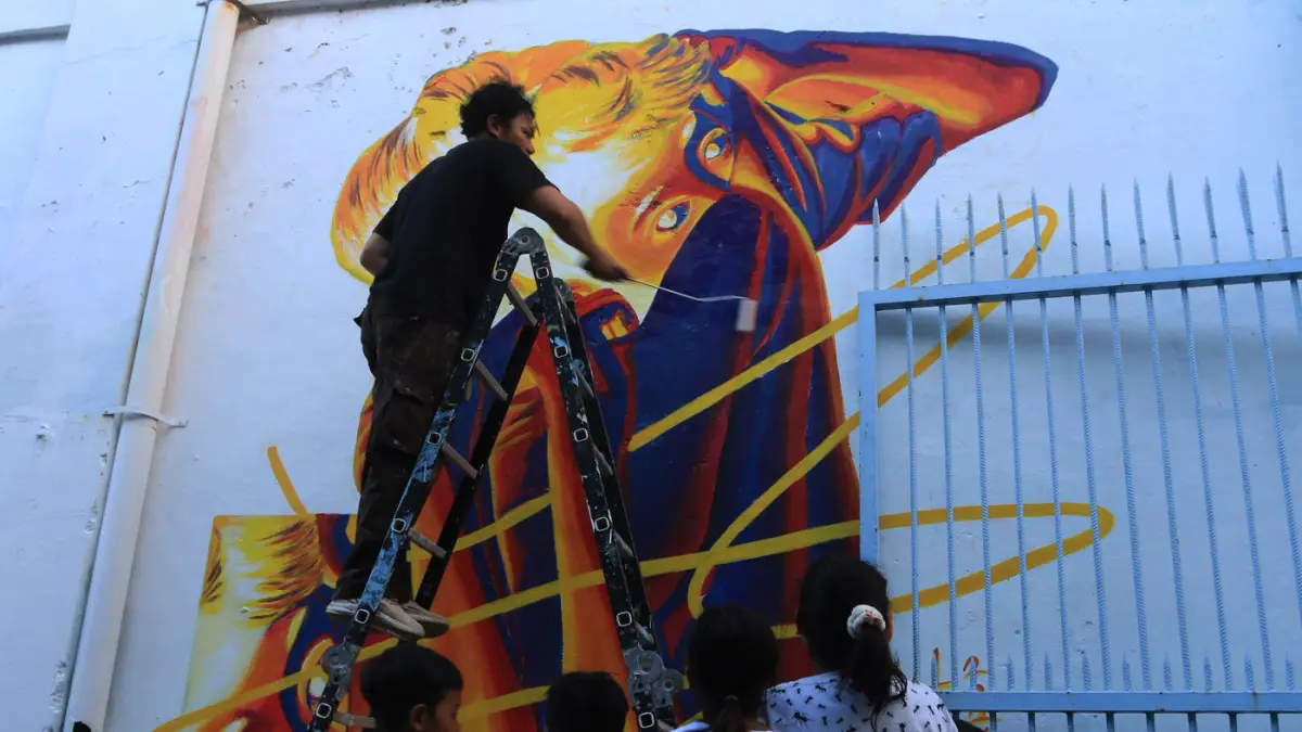 Seniman menyelesaikan mural bertema “Aturan Awuren” di tembok Kampung Petemesan, Pekojan, Semarang. (Nur Chamim/ Jawa Pos Radar Semarang)