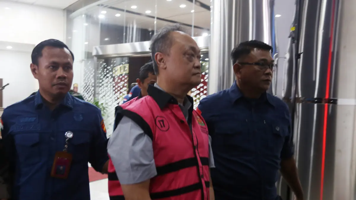 Petugas mendampingi tersangka perkara dugaan pengadaan minyak mentah dan produk kilang Irawan Prakoso usai menjalani pemeriksaan di Kejaksaan Agung, Jakarta, Kamis (9/4/2026). (Dery Ridwansah/ JawaPos.com)