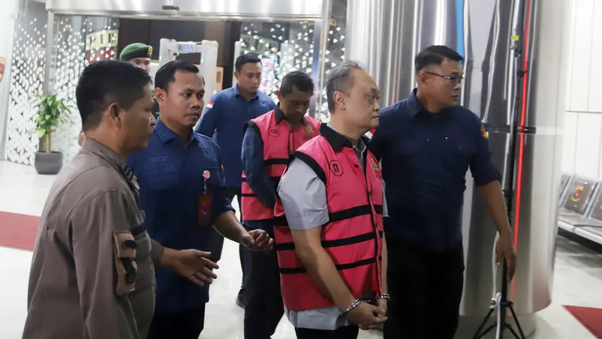 Petugas mendampingi tersangka perkara dugaan pengadaan minyak mentah dan produk kilang Irawan Prakoso usai menjalani pemeriksaan di Kejaksaan Agung, Jakarta, Kamis (9/4/2026). (Dery Ridwansah/ JawaPos.com)