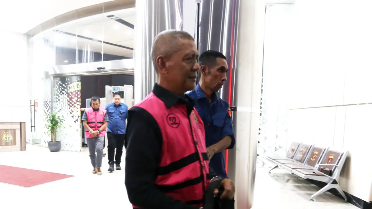 Petugas mendampingi tersangka perkara dugaan pengadaan minyak mentah dan produk kilang Tafkir Husni usai menjalani pemeriksaan di Kejaksaan Agung, Jakarta, Kamis (9/4/2026). (Dery Ridwansah/ JawaPos.com)