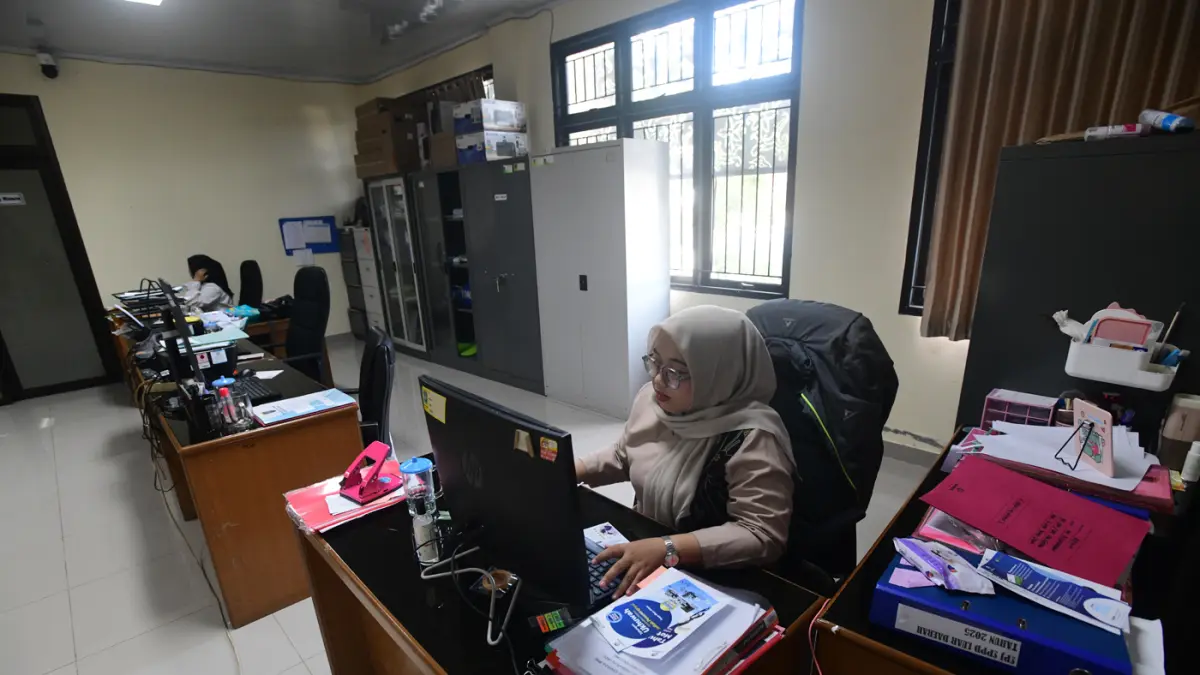 Staf bekerja di depan komputer dengan beberapa meja kursi yang kosong saat penerapan work from home (WFH) bagi aparatur sipil negara (ASN) di kantoir Kecamatan Limo, Depok, Jumat (10/04/2026). (Dery Ridwansah/ JawaPos.com)