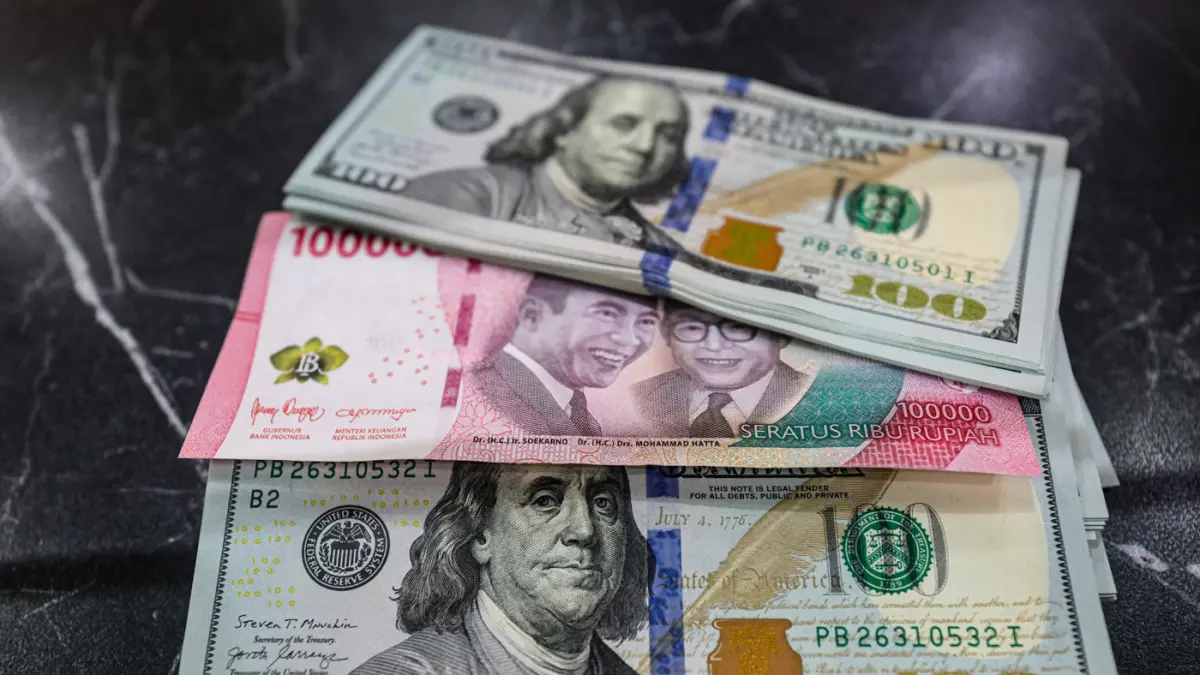 Pegawai menunjukan mata uang dolar AS dan rupiah di salah satu gerai penukaran mata uang asing di Jakarta, Selasa (14/4/2026). (Salman Toyibi/Jawa Pos)