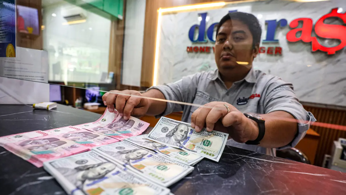 Pegawai menunjukan mata uang dolar AS dan rupiah di salah satu gerai penukaran mata uang asing di Jakarta, Selasa (14/4/2026). (Salman Toyibi/Jawa Pos)