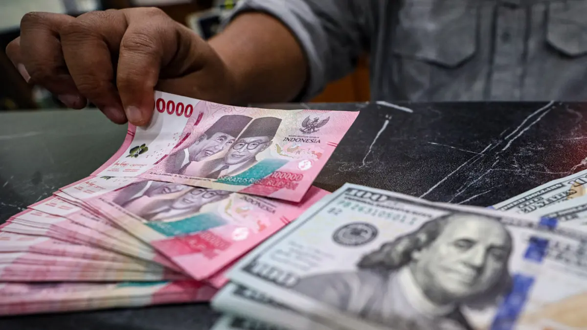 Pegawai menunjukan mata uang dolar AS dan rupiah di salah satu gerai penukaran mata uang asing di Jakarta, Selasa (14/4/2026). (Salman Toyibi/Jawa Pos)
