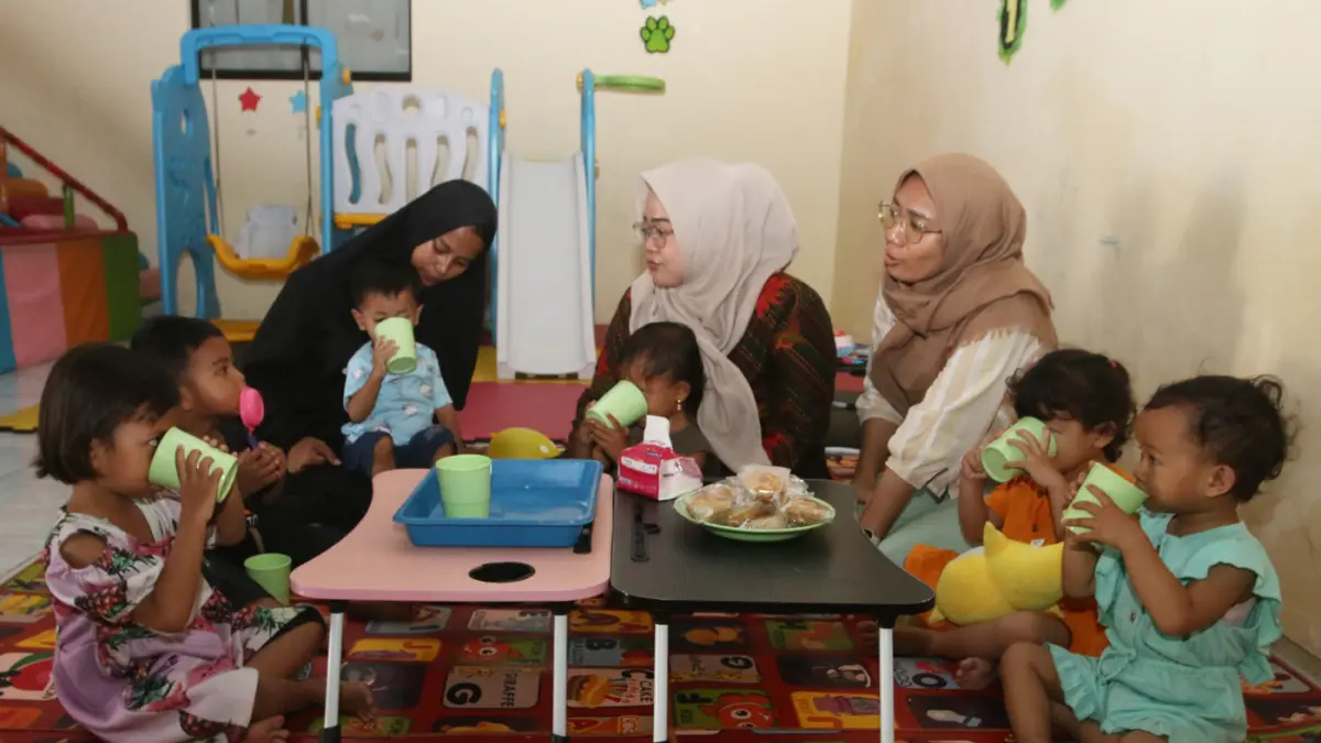 Pendamping menemani anak balita saat minum susu di Rumah Pelita, Manyaran, Semarang, Jawa Tengah, Senin (13/4/2026). (Nur Chamim/Jawa Pos Radar Semarang)