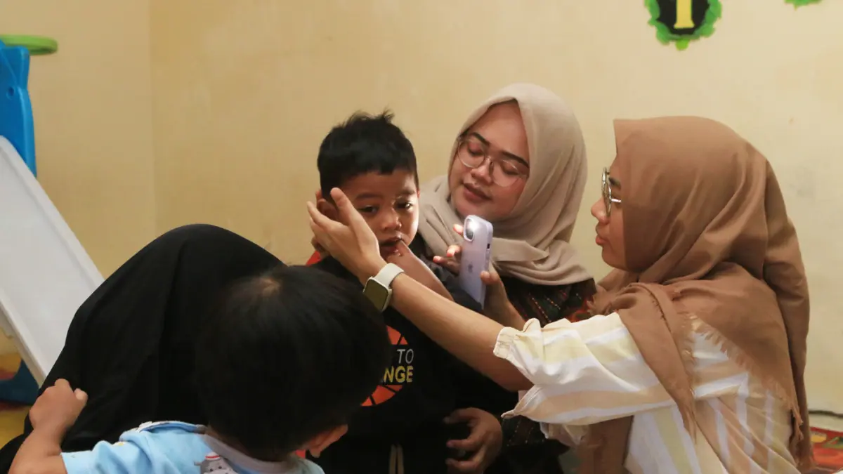 Pendamping menemani anak balita saat minum susu di Rumah Pelita, Manyaran, Semarang, Jawa Tengah, Senin (13/4/2026). (Nur Chamim/Jawa Pos Radar Semarang)
