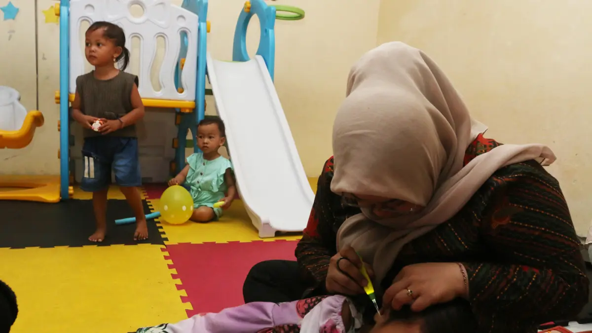 Pendamping menemani anak balita saat minum susu di Rumah Pelita, Manyaran, Semarang, Jawa Tengah, Senin (13/4/2026). (Nur Chamim/Jawa Pos Radar Semarang)