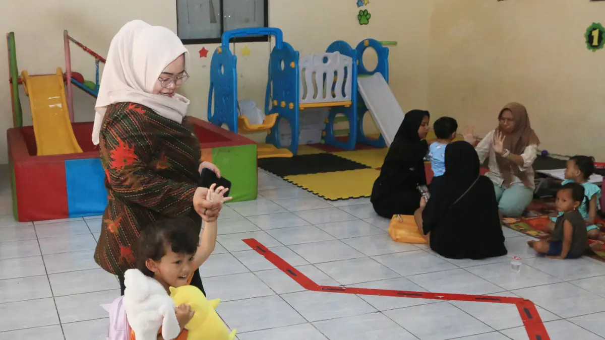 Pendamping menemani anak balita saat minum susu di Rumah Pelita, Manyaran, Semarang, Jawa Tengah, Senin (13/4/2026). (Nur Chamim/Jawa Pos Radar Semarang)
