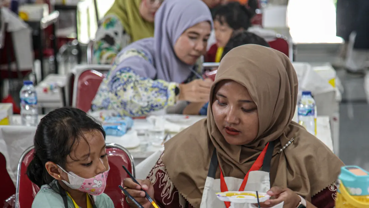 Sejumlah anak-anak didampingi orang tua mewarnai tas kanvas saat kegiatan Re:Art LRT Jakarta Art for Happy Moms and Kids di Stasiun LRT Pulomas, Jakarta, Minggu (19/04/2026). (Hanung Hambara/Jawa Pos)