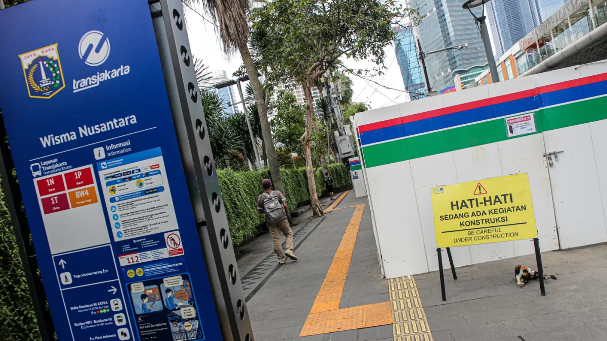 Pejalan kaki berjalan di samping proyek revitalisasi area Stasiun MRT BuPekerja konstruksi beraktifitas di proyek revitalisasi area Stasiun MRT Bundaran HI Bank Jakarta di Jalan MH Thamrin, Jakarta, Jumat (24/04/2035). (Hanung Hambara/Jawa Pos)