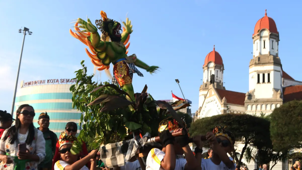 Warga menyambut kemeriahan Karnaval Seni Budaya Lintas Agama atau Pawai Ogoh-ogoh melintas di lawang sewu Kota Semarang (26/4/2026). (Nur Chamim/Jawa Pos Radar Semarang)
