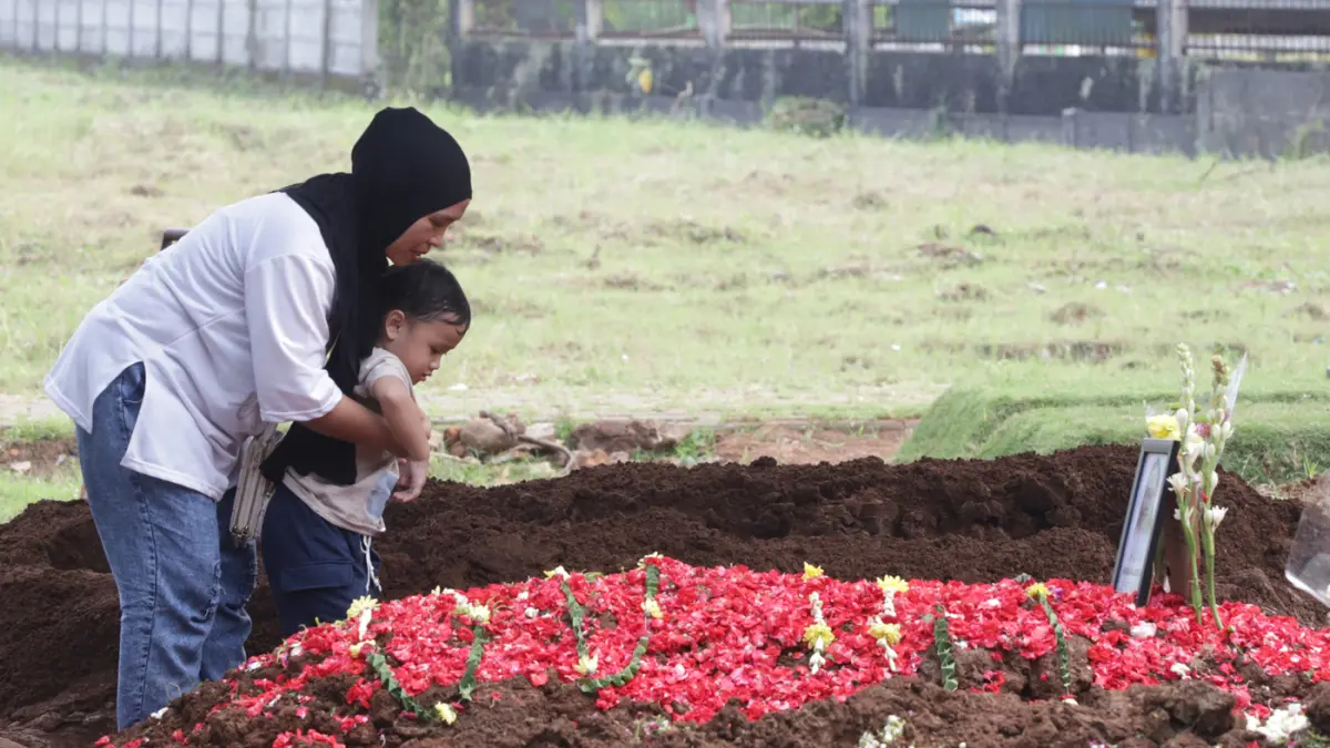 Sang anak almarhumah Harum Anjasari menyiramkan air kemakam sang ibu di Tempat Pemakaman Umum (TPU) Cipayung, Jakarta Timur, Rabu (29/4/2026). (Dery Ridwansah/ JawaPos.com)