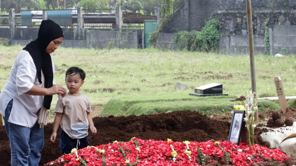 Sang anak almarhumah Harum Anjasari menyiramkan air kemakam sang ibu di Tempat Pemakaman Umum (TPU) Cipayung, Jakarta Timur, Rabu (29/4/2026). (Dery Ridwansah/ JawaPos.com)