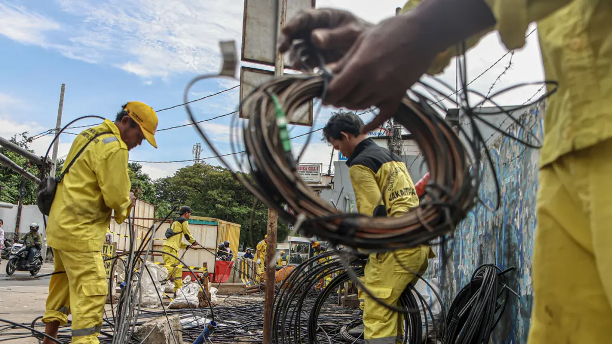 Sejumlah petugas dari Suku Dinas Bina Marga Jakarta Barat membersihkan potongan kabel utilitas di Jalan Peta Barat, Jakarta, Selasa (05/05/2026). (Hanung Hambara/Jawa Pos)