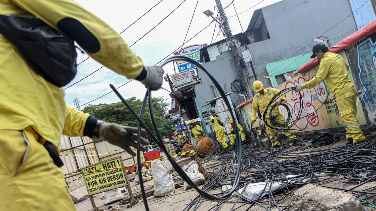 Sejumlah petugas dari Suku Dinas Bina Marga Jakarta Barat membersihkan potongan kabel utilitas di Jalan Peta Barat, Jakarta, Selasa (05/05/2026). (Hanung Hambara/Jawa Pos)