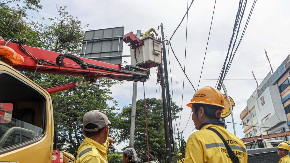 Sejumlah petugas dari Suku Dinas Bina Marga Jakarta Barat membersihkan potongan kabel utilitas di Jalan Peta Barat, Jakarta, Selasa (05/05/2026). (Hanung Hambara/Jawa Pos)