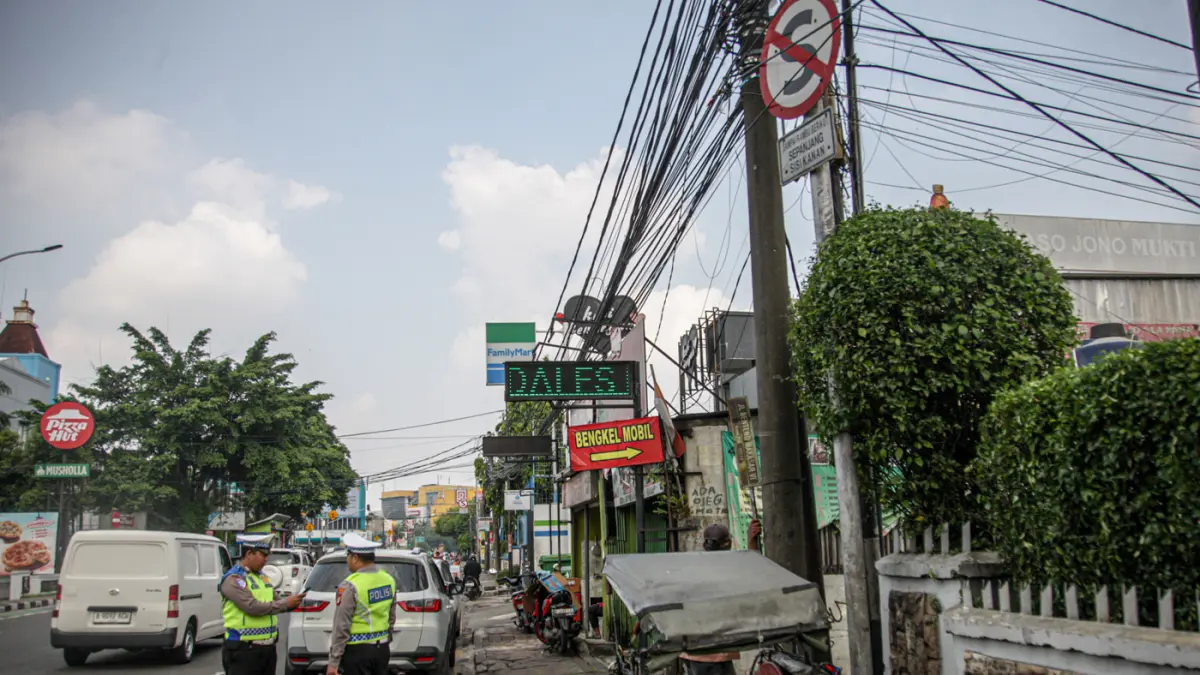 Anggota Satlantas Polres Metro Tangerang Kota melakukan pendindakan parkir liar dengan tilang ETLE Handheld di jalan Daan Mogot, Kota Tangerang, Kamis (07/05/2025). (Hanung Hambara/Jawa Pos)