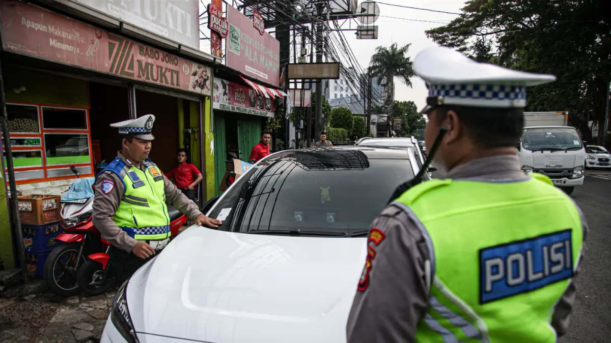 Anggota Satlantas Polres Metro Tangerang Kota melakukan pendindakan parkir liar dengan tilang ETLE Handheld di jalan Daan Mogot, Kota Tangerang, Kamis (07/05/2025). (Hanung Hambara/Jawa Pos)