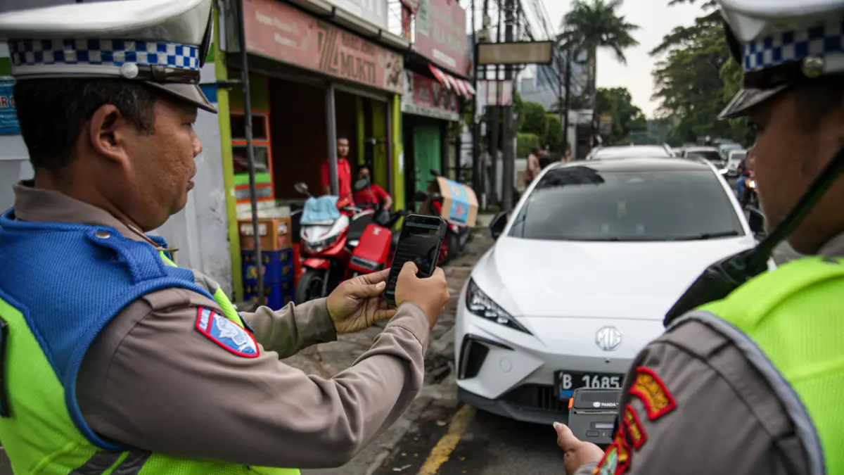 Anggota Satlantas Polres Metro Tangerang Kota melakukan pendindakan parkir liar dengan tilang ETLE Handheld di jalan Daan Mogot, Kota Tangerang, Kamis (07/05/2025). (Hanung Hambara/Jawa Pos)