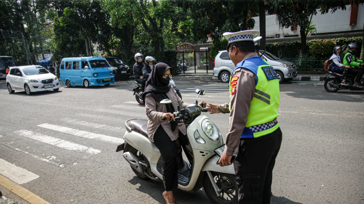 Anggota Satlantas Polres Metro Tangerang Kota melakukan pendindakan parkir liar dengan tilang ETLE Handheld di jalan Daan Mogot, Kota Tangerang, Kamis (07/05/2025). (Hanung Hambara/Jawa Pos)