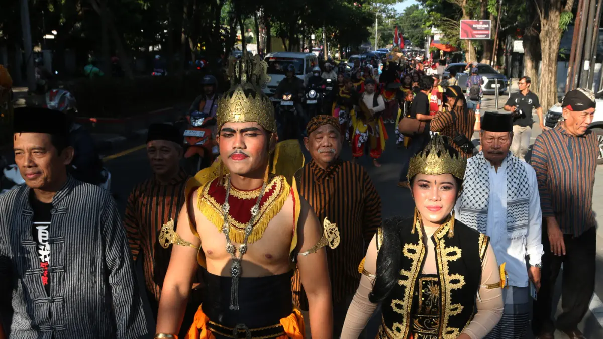 Lurah Gisikdrono Sandy Inderawan bersama istri, Damara Wibowo, mengenakan kostum pewayangan Rama dan Sinta saat memimpin kirab budaya apitan di Kelurahan Gisikdrono, Kecamatan Semarang Barat, Kamis (7/5/2026). (Nur Chamim/Jawa Pos Radar Semarang)
