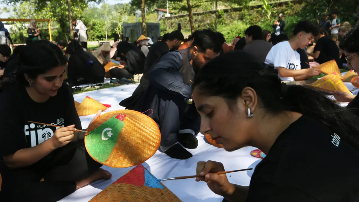 Sejumlah mahasiswa asing melukis caping pada Summer Course UNNES 2026 di desa wisata Kandri, Kota Semarang. (Nur Chamim/Jawa Pos Radar Semarang)