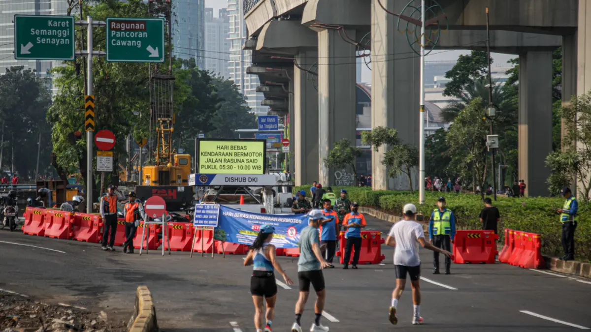Petugas memberi himbauan saat penutupan jalan untuk HBKB di ruas jalan Rasuna Sadi, Jakarta, Minggu (10/05/2026). (Hanung Hambara/Jawa Pos)