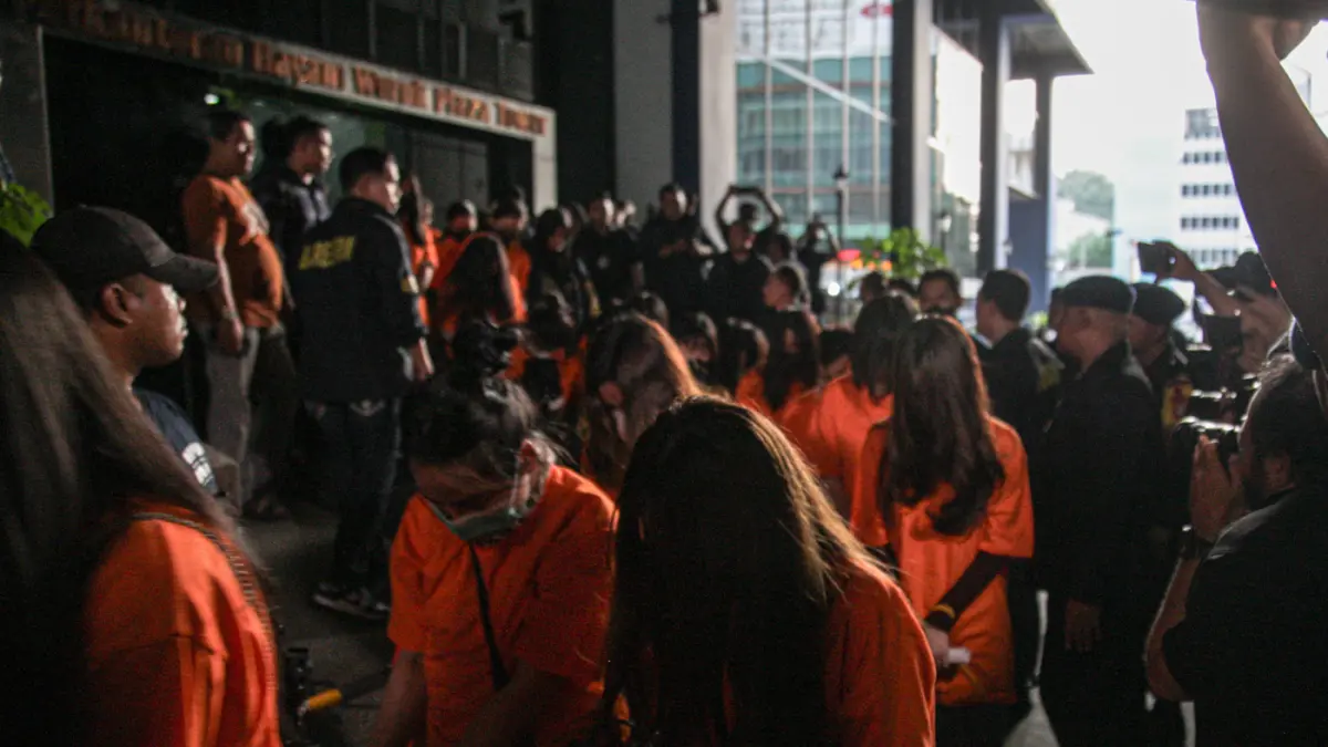 Sejumlah tersangka judi online (judol) dikawal ketat oleh aparat Kepolisian keluar dari Hayam Wuruk Tower, Jakarta, Minggu (10/05/2026). Tim gabungan Bareskrim Polri dan Polda Metro Jaya mengamankan 321 orang yang terdiri 321 WNA yang diamankan, terdiri d