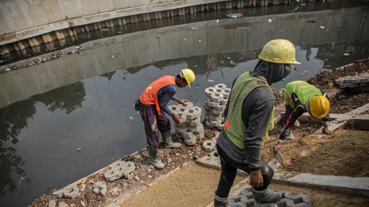 Sejumlah pekerja melakukan pemasangan paving blok di sepadan aliran Kali Grogol, Jakarta, (11/05/2026). (Hanung Hambara/Jawa Pos)