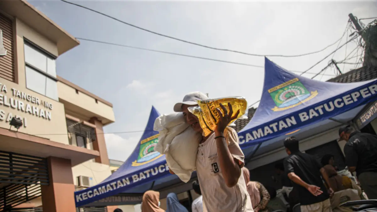 Warga penerima bantuan pangan membawa sejumlah bantuan berupa beras dan minyak goreng saat penyaluran bantuan Keluarga Penerima Manfaat (KPM) di Kantor Kelurahan Batusari, Kota Tangerang, Kamis (14/5/2026). (Hanung Hambara/Jawa Pos)