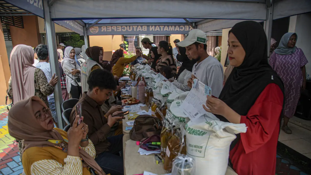 Warga penerima bantuan pangan membawa sejumlah bantuan berupa beras dan minyak goreng saat penyaluran bantuan Keluarga Penerima Manfaat (KPM) di Kantor Kelurahan Batusari, Kota Tangerang, Kamis (14/5/2026). (Hanung Hambara/Jawa Pos)