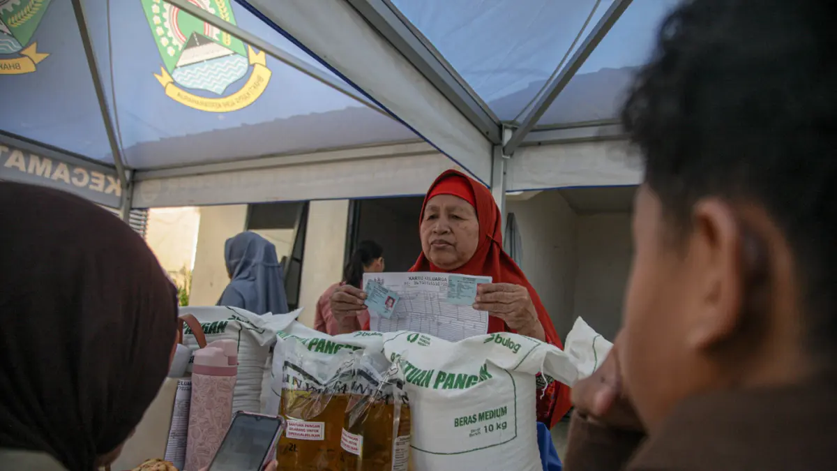 Warga penerima bantuan pangan membawa sejumlah bantuan berupa beras dan minyak goreng saat penyaluran bantuan Keluarga Penerima Manfaat (KPM) di Kantor Kelurahan Batusari, Kota Tangerang, Kamis (14/5/2026). (Hanung Hambara/Jawa Pos)