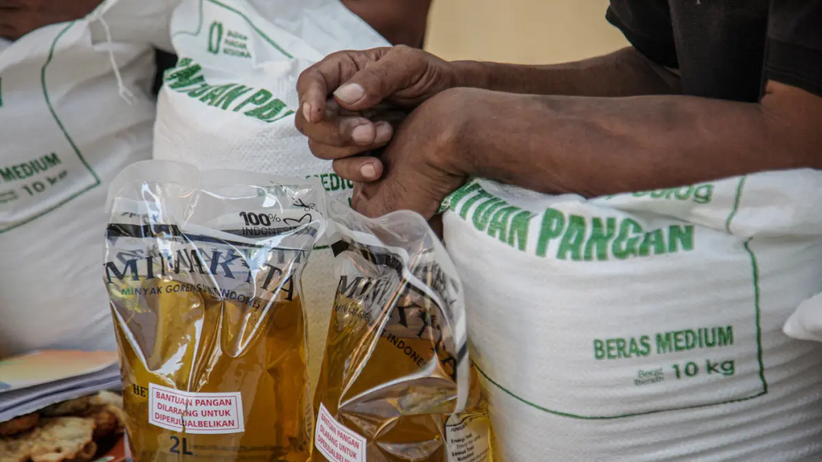 Warga penerima bantuan pangan membawa sejumlah bantuan berupa beras dan minyak goreng saat penyaluran bantuan Keluarga Penerima Manfaat (KPM) di Kantor Kelurahan Batusari, Kota Tangerang, Kamis (14/5/2026). (Hanung Hambara/Jawa Pos)