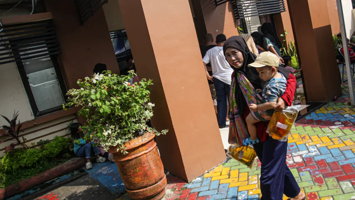 Warga penerima bantuan pangan membawa sejumlah bantuan berupa beras dan minyak goreng saat penyaluran bantuan Keluarga Penerima Manfaat (KPM) di Kantor Kelurahan Batusari, Kota Tangerang, Kamis (14/5/2026). (Hanung Hambara/Jawa Pos)