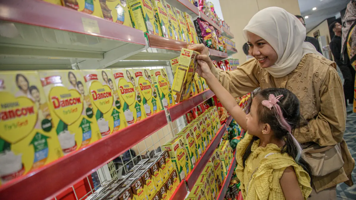 Seorang anak didampingi orang tua memilih produk susu DANCOW saat acara Kompetisi DANCOW Indonesia Cerdas Season 2 di Jakarta, Senin (18/05/2026). (Hanung Hambara/ Jawa Pos)