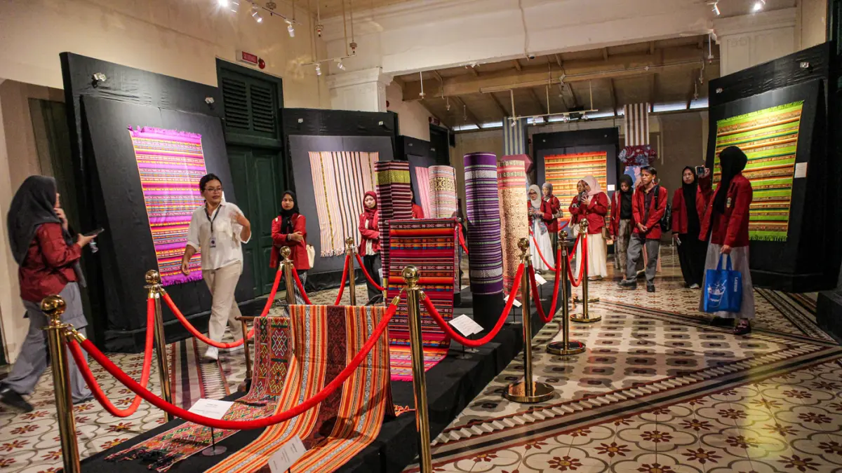 Pengunjung melihat perpaduan koleksi kain tenun dari Ekuador dan Nusa Tenggara (Indonesia) di pameran Menenun Warna Tanpa Batas Indonesia dan Ekuador di Museum Tekstil, Jakarta, Minggu (17/05/2026). (Hanung Hambara/Jawa Pos)