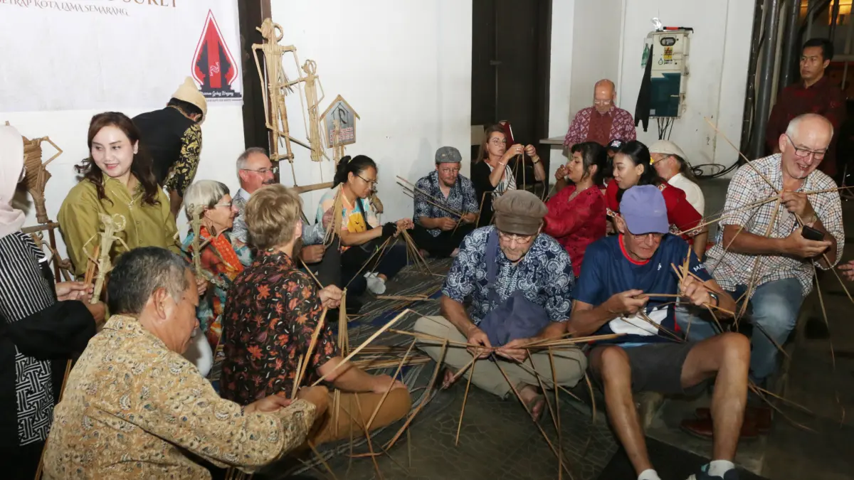 Peserta sepeda tua internasional dari berbagai negara belajar membuat Wayang Suket di halaman Gedung Oudetrap, Kota Lama Semarang, Kamis (28/5/2026). (Nur Chamim/Jawa Pos Radar Semarang)
